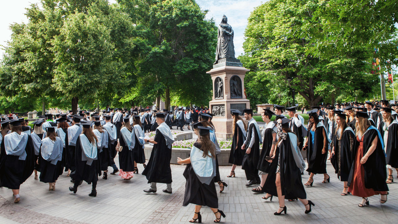 A row of University of Canterbury graduates, wearing academic regalia, file into the Christchurch Town Hall.