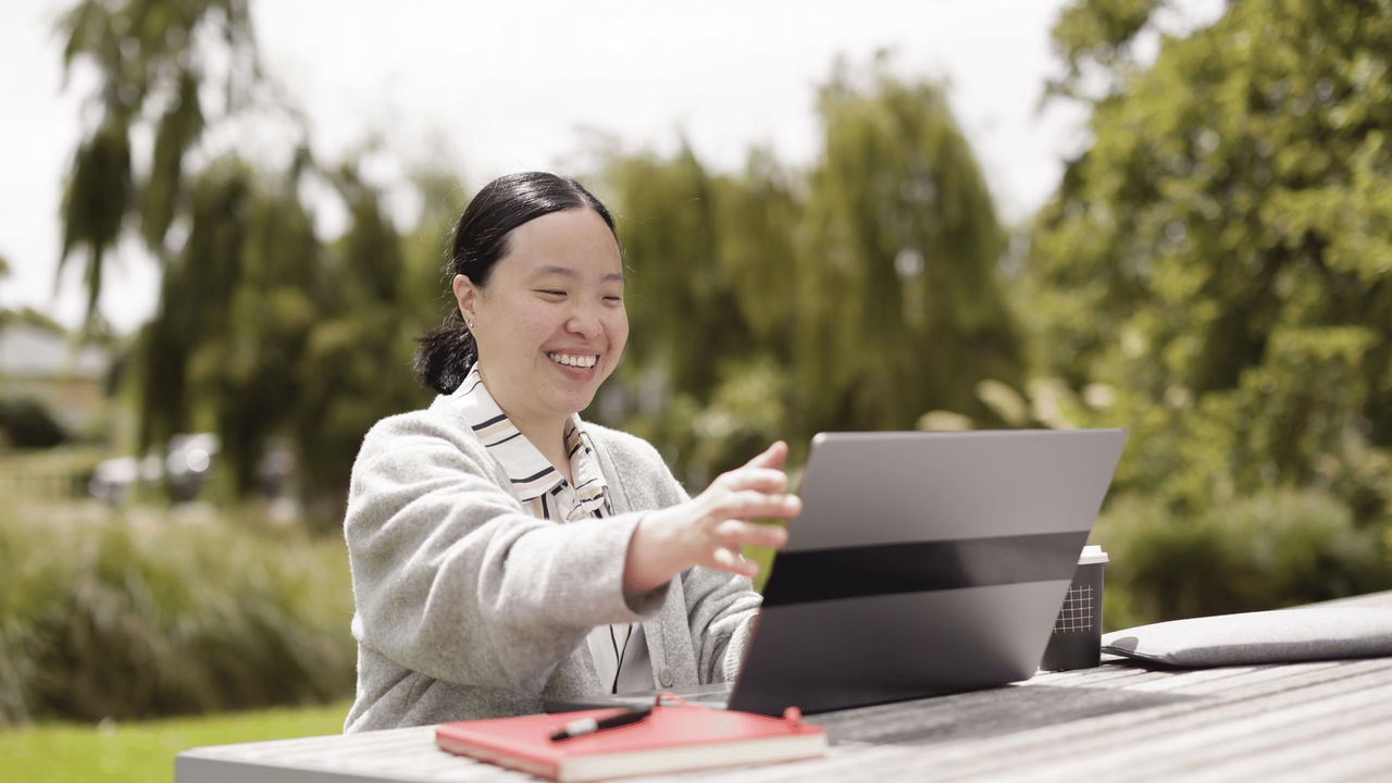Woman learning online studies outside as part of her UC Online coursework
