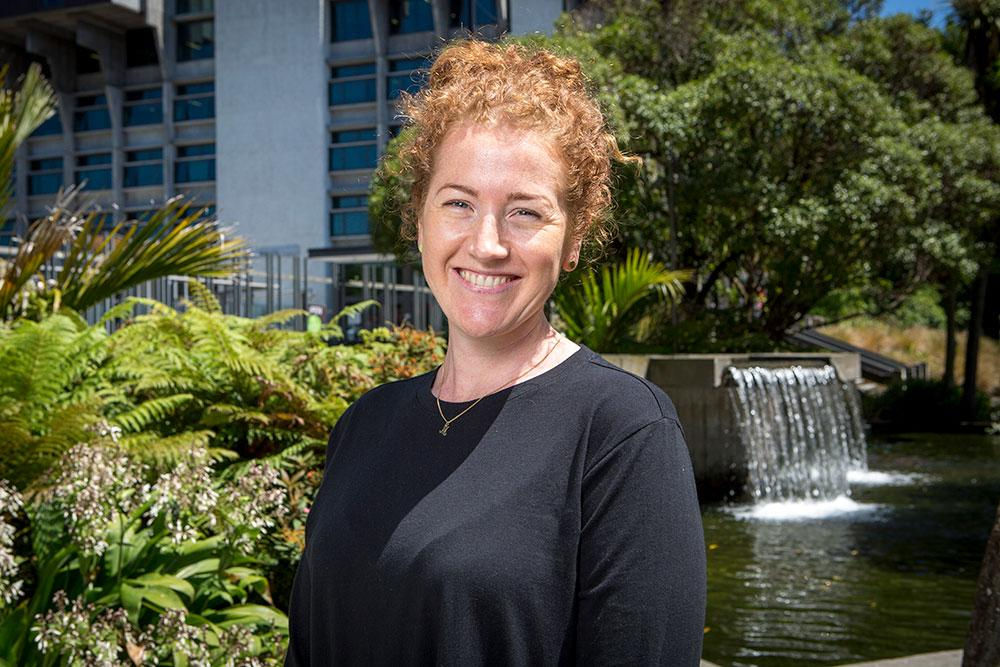A professional woman greets UC Online team members before a meeting about staff training and development options.