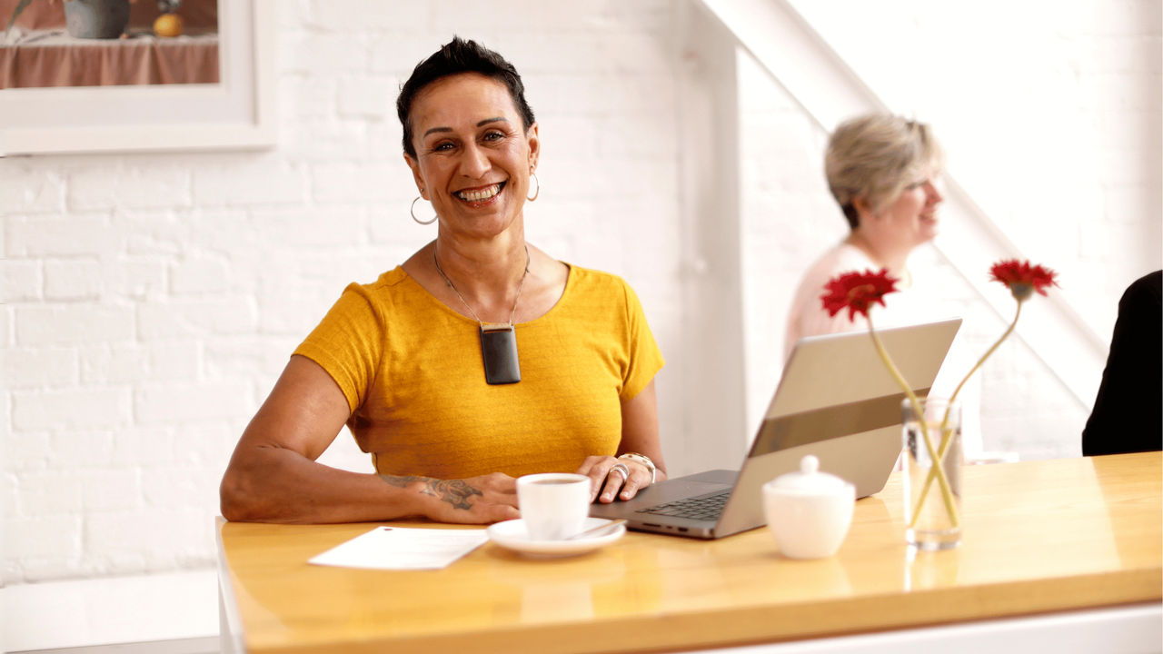 A manager uses a laptop to show a staff member how to complete an administrative task.