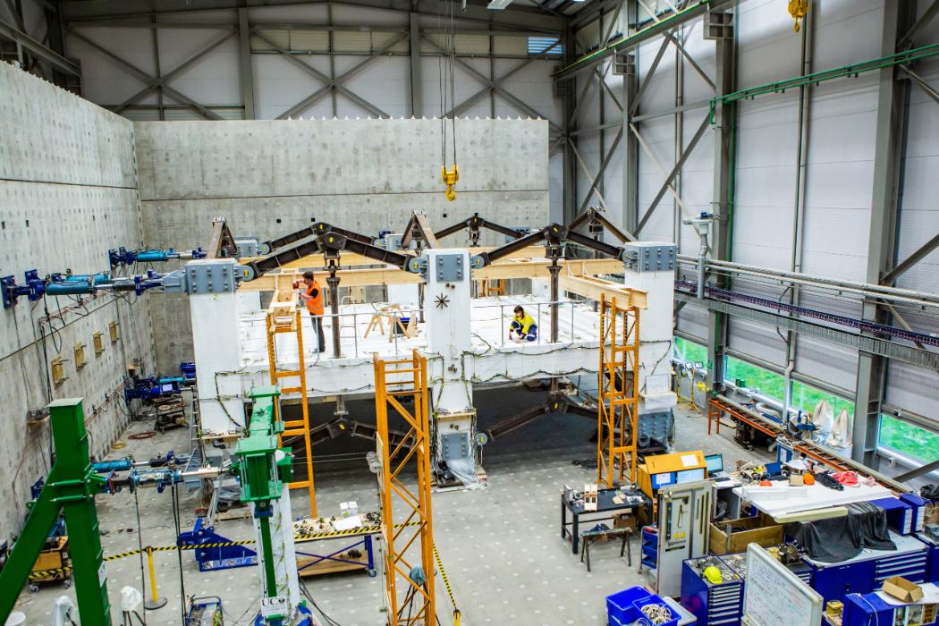 Large concrete warehouse with a foundation structure in the middle being constructed by people wearing high-vis.