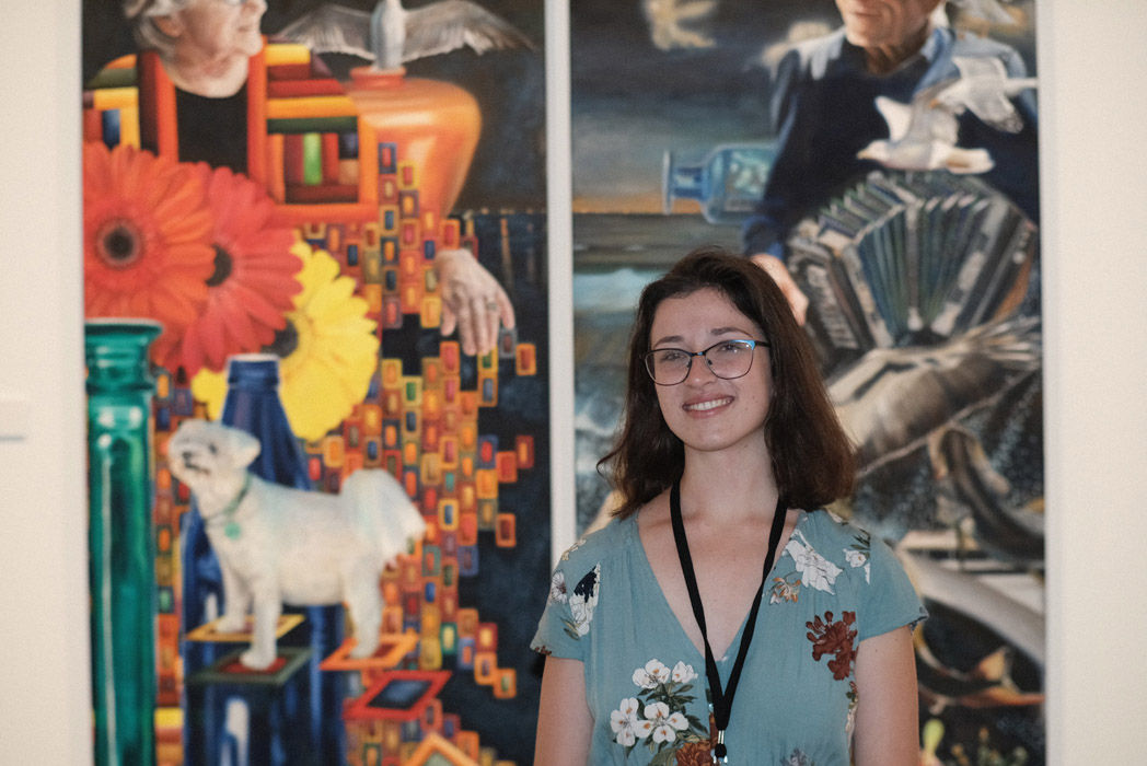 Photo of Hazel Rae standing in front of her paintings 