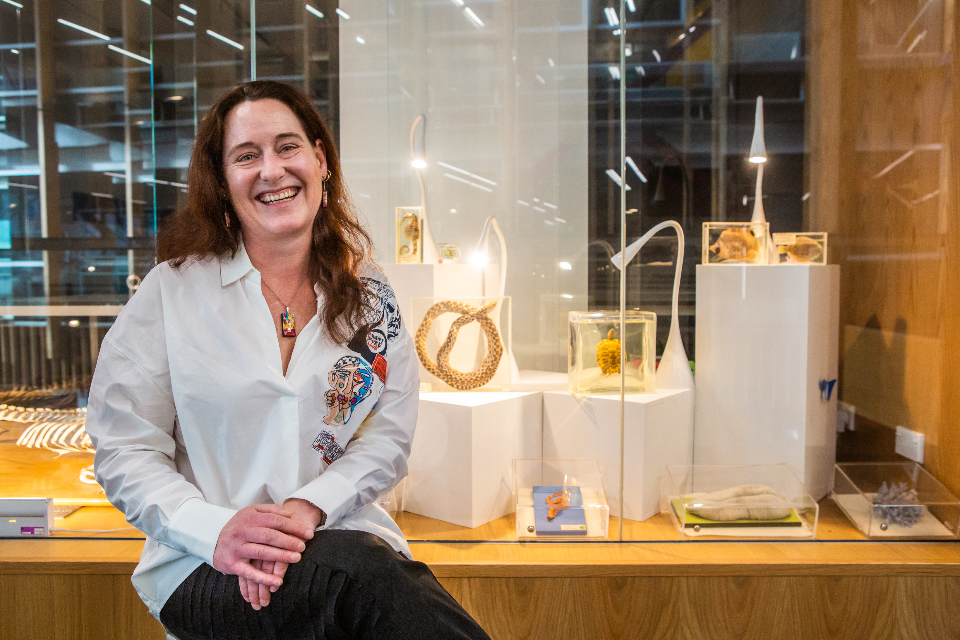 Person sitting next to a glass exhibit display of animal models.