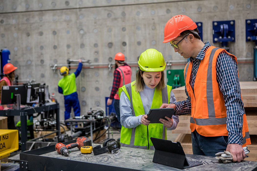 A student wearing high-vis discussing plans with a lecturer in UC's Structural Engineering Lab.