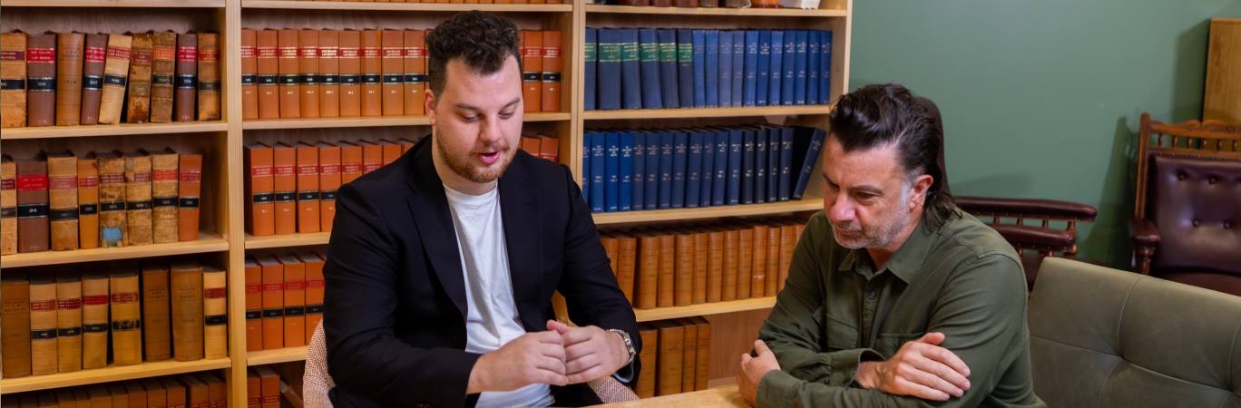 UC student and staff member looking at a laptop