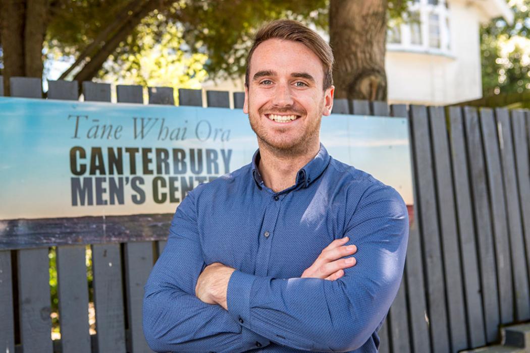 A UC student standing outsite of a Canterbury Men's Centre.