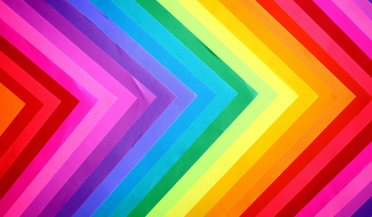 Rainbow paper triangles arranged in a gradient with the points of the triangles pointing right
