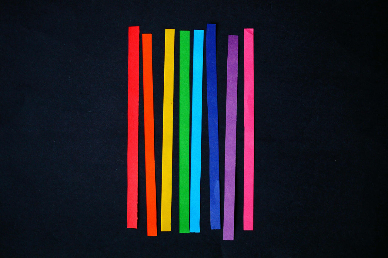 Vertical rainbow paper strips on a black background