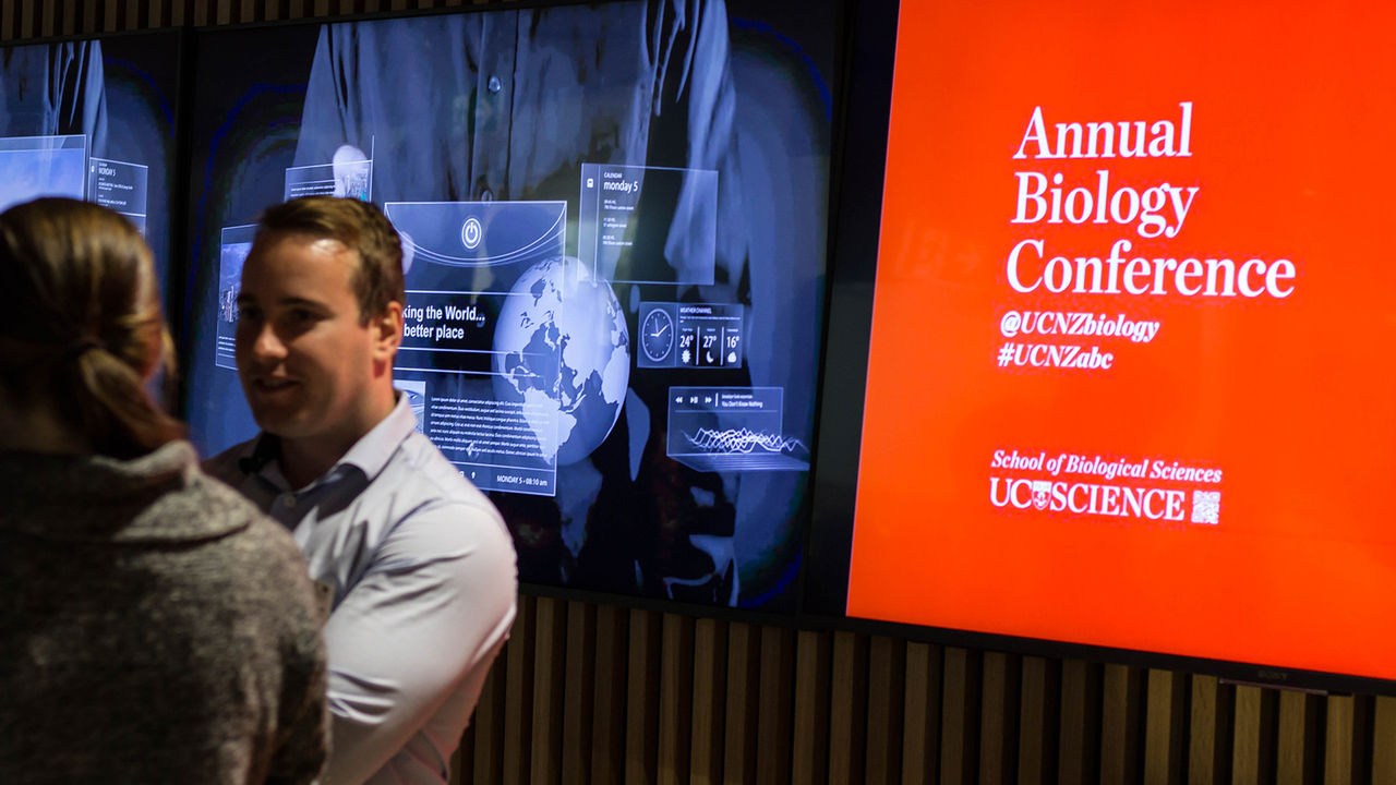 People talking in front of a conference sign