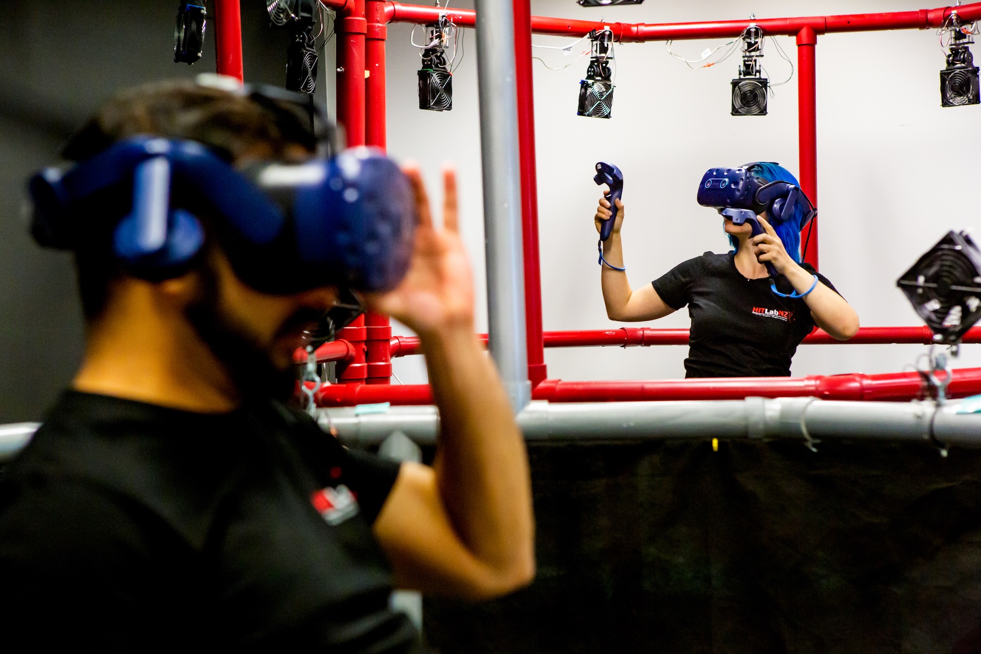 Two people wearing virtual reality headsets and using controllers.