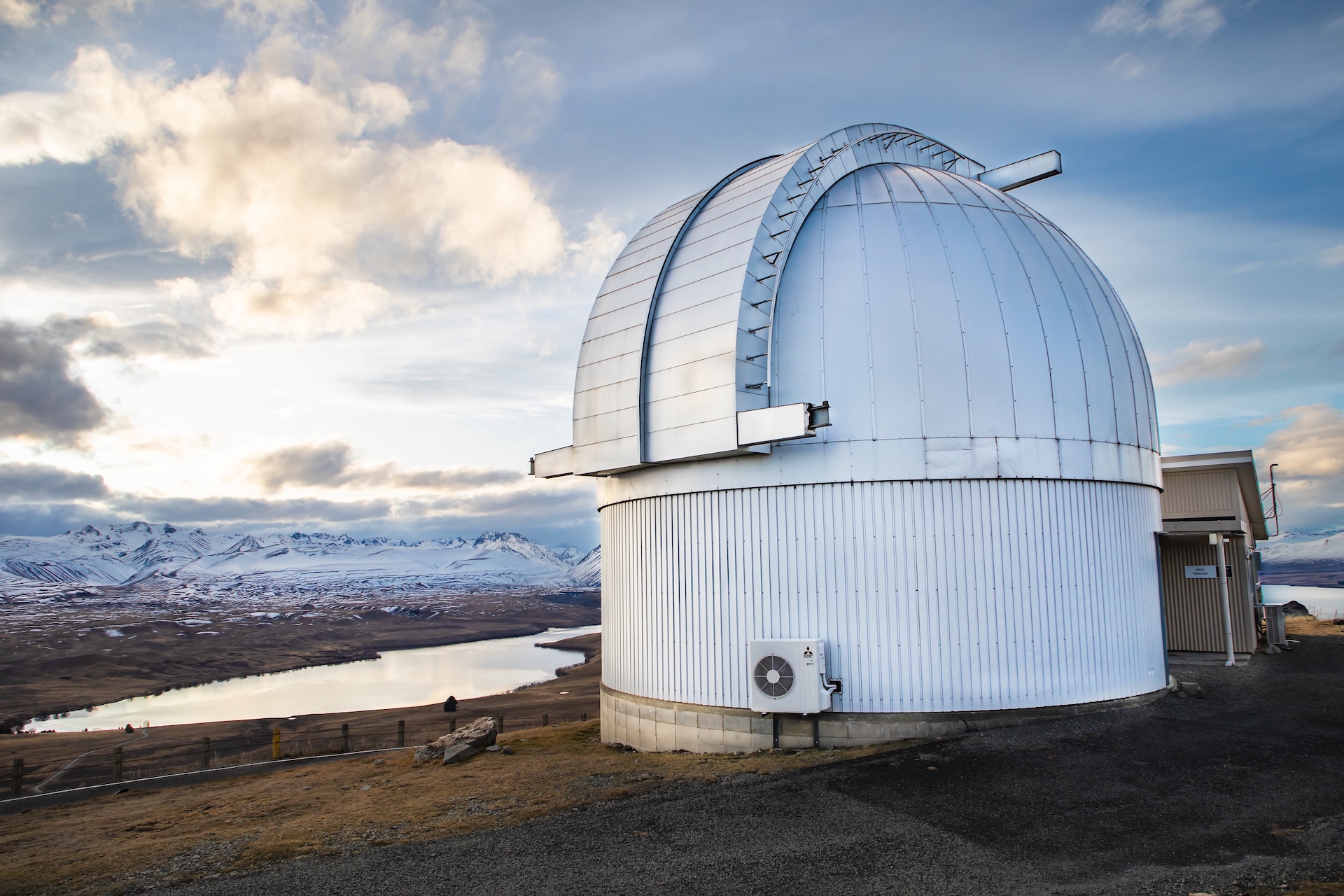 Mount John Observatory with snowy mountains in the background.