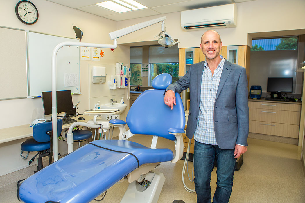 Person standing beside a dental examining chair.