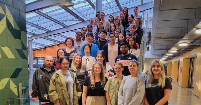 A cohort of UC Online Master of Health Sciences (Nursing) students stand on a stairwell for a group photograph.