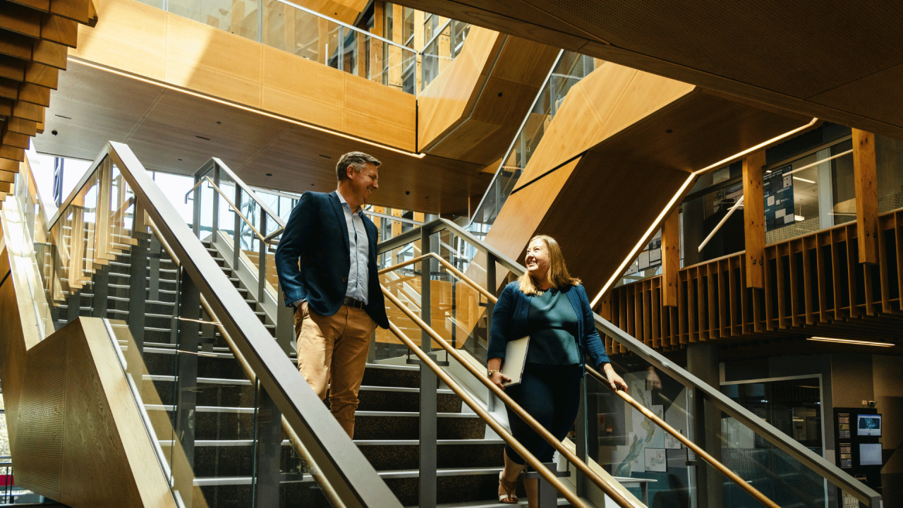 Strategic communication leaders walk down the stairs discussing their online Master of Strategic Communication learner. 