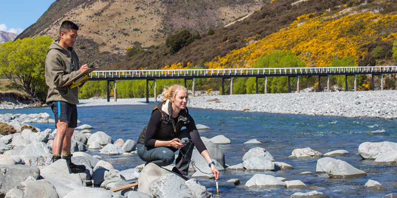 Two UC researchers measuring water quality at a river in Cass New Zealand.