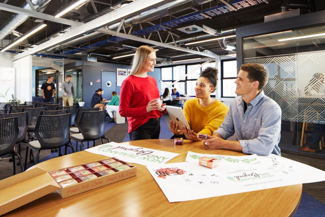 Students chat at a table in a shared workspace.