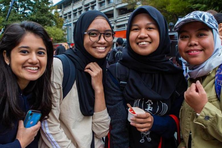 Four students smile whilst attending an event on campus.