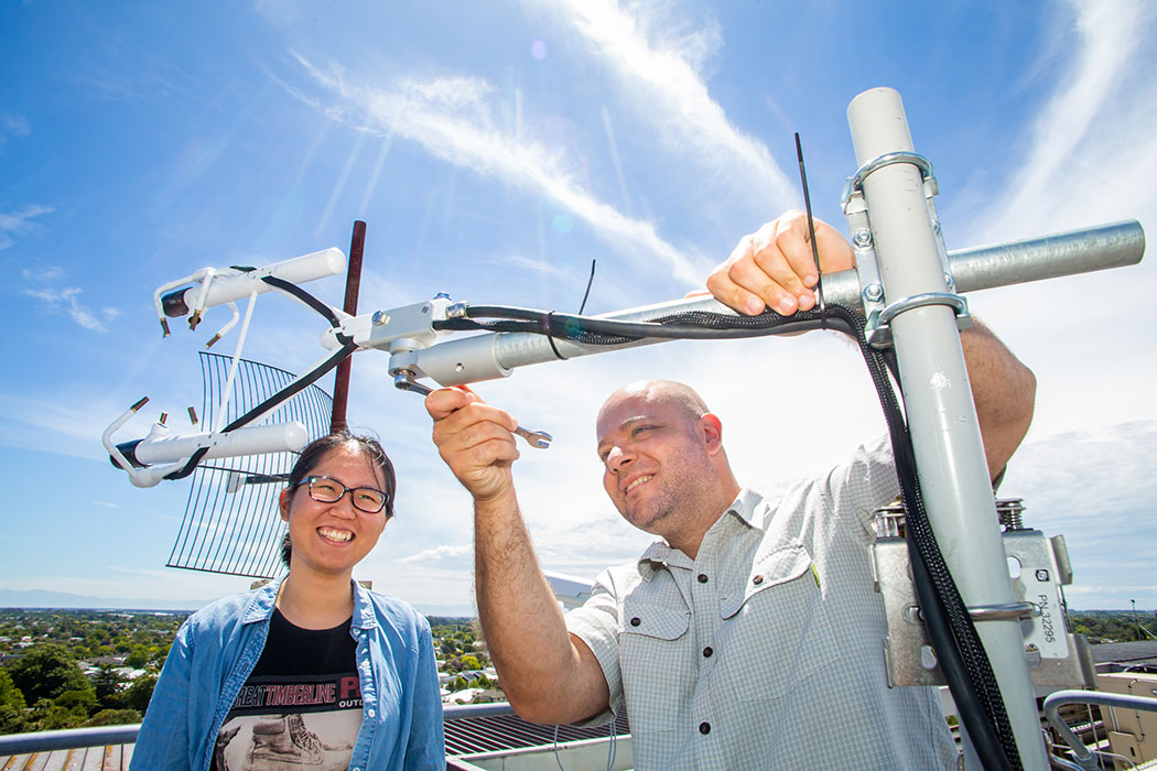 UC researchers Marwin Katurji and Donqi Lin working on an antenna on a building roof.