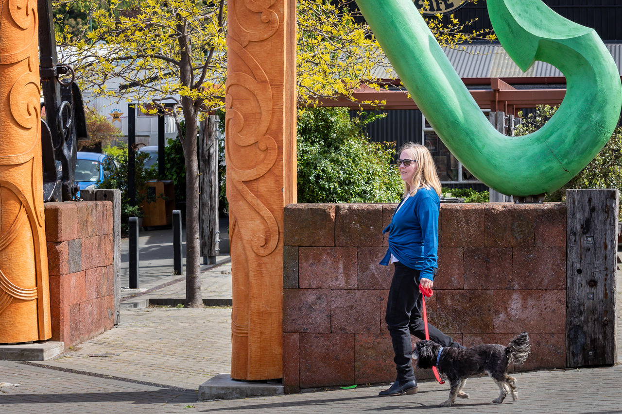 Professor Lucie Ozanne walking along a footpath with a small black dog on a lead.