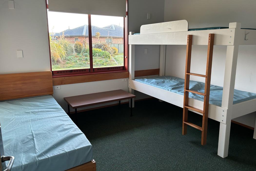 Small bedroom with a bunkbed against one wall and a single bed against the other.