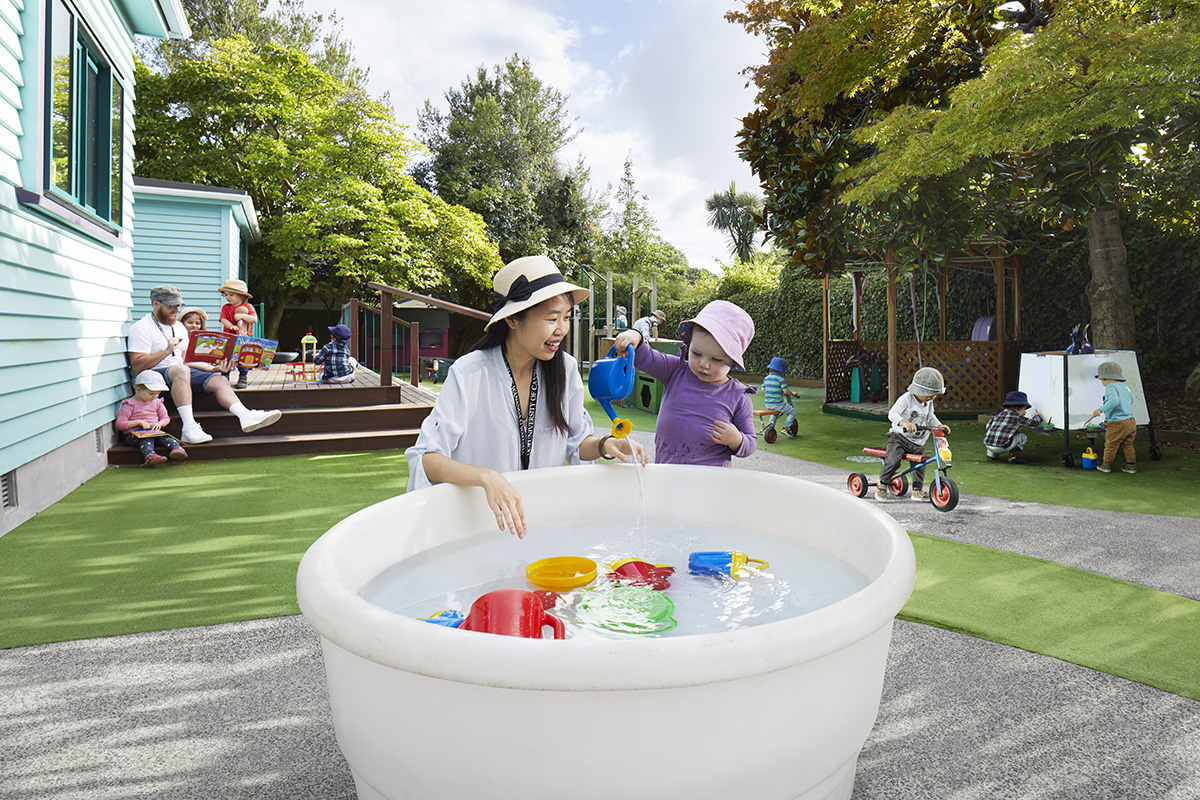Early childhood teacher playing at water play station with child