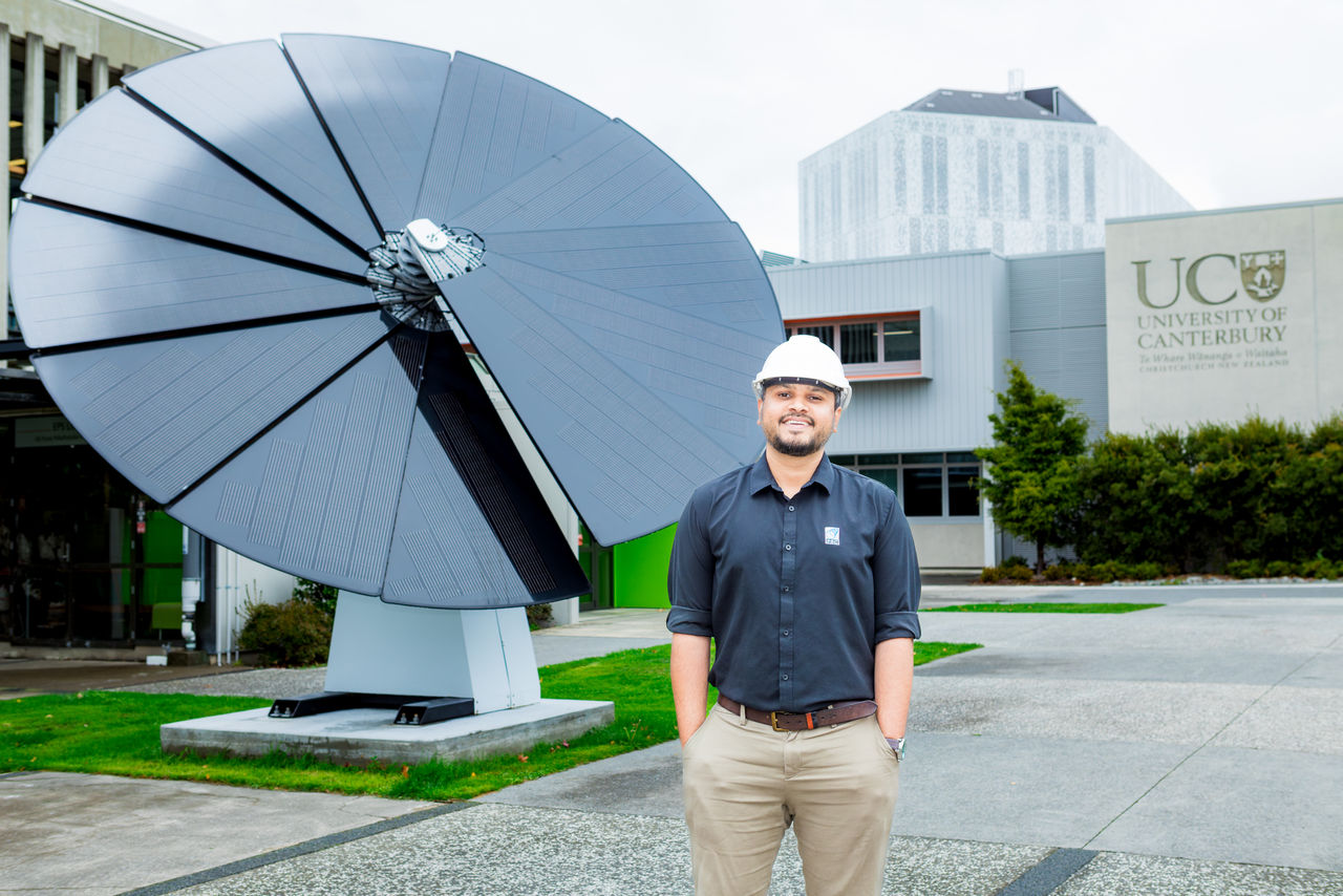 A UC engineer stands in front of the 5 metre tall 'Solar Sunflower' solar panel scultpure on the lawn outside of the Rehua building.