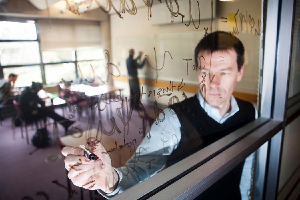 Mathematics lecturer writing on a glass window in teaching room