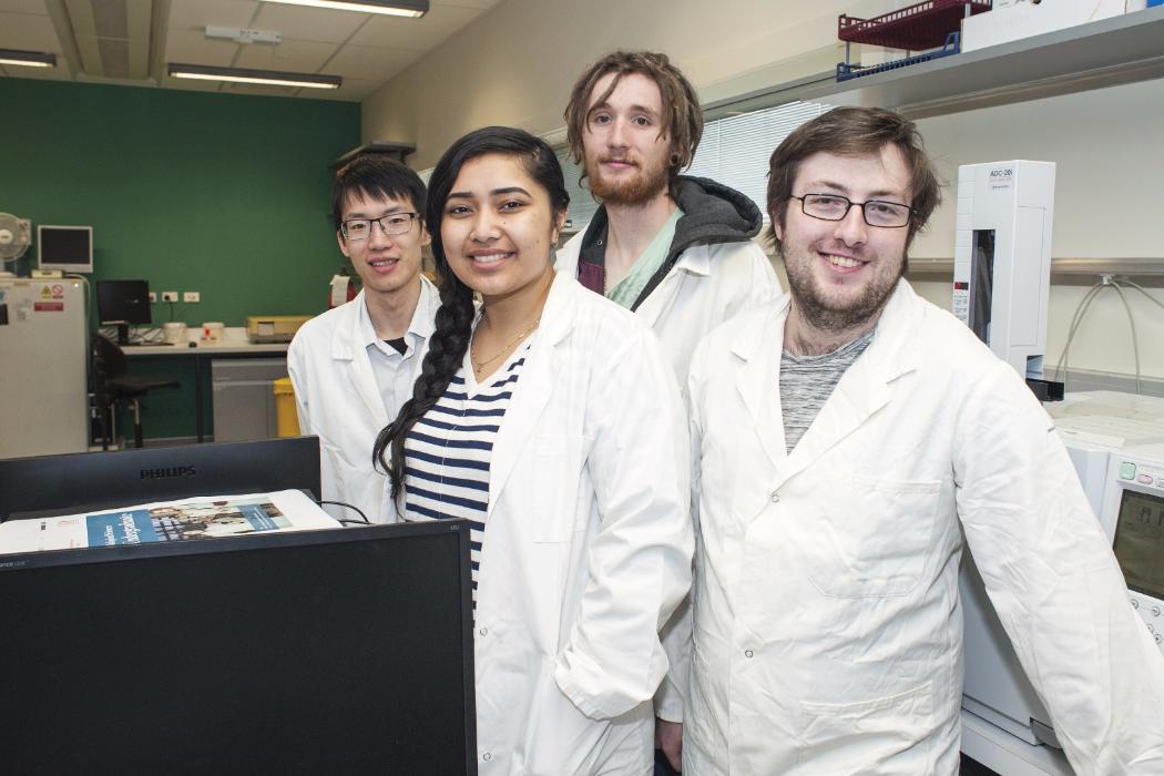 Four Biology Students in Lab Wearing White Coats