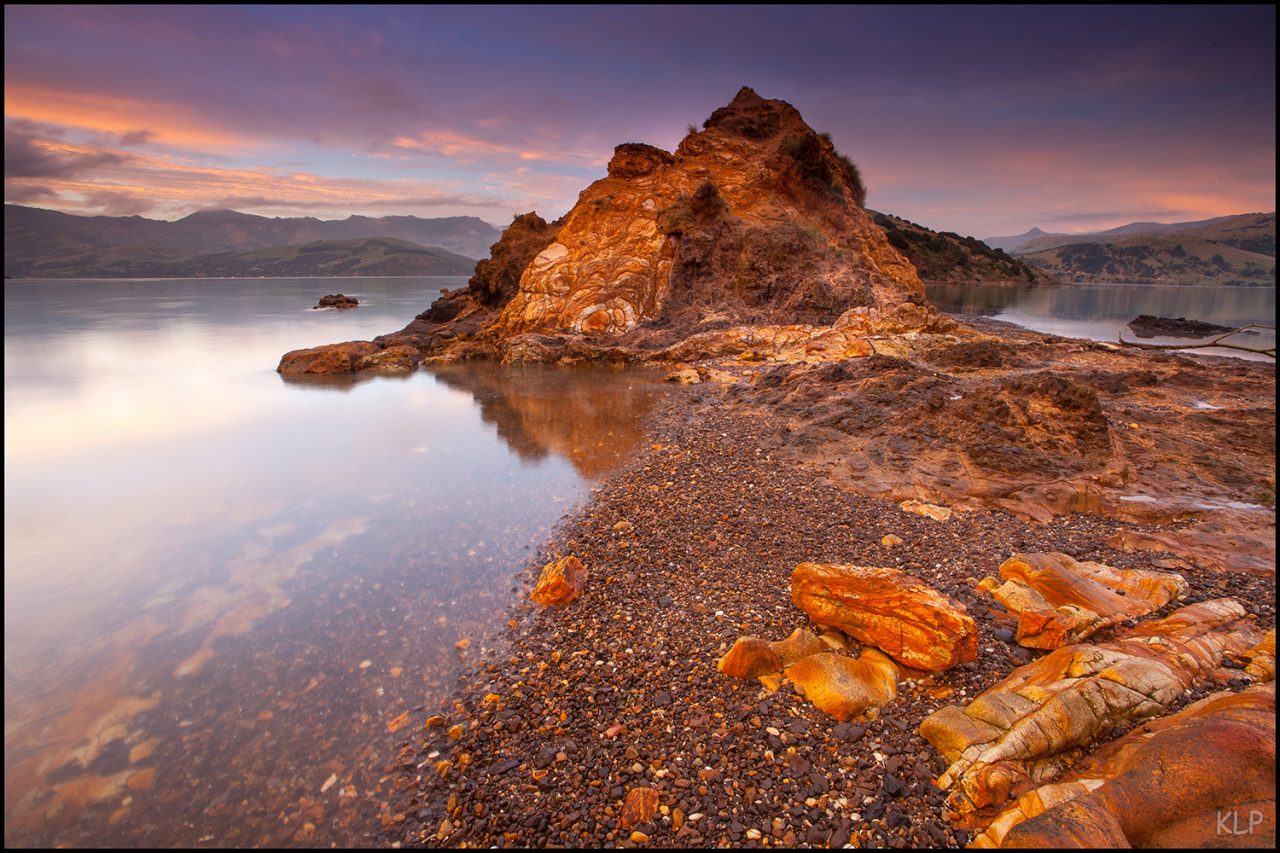 Trachyte at Onawe Peninsula, Akaroa, in the form of a dike. Intruding up through surrounding rocks next to the waterfront.