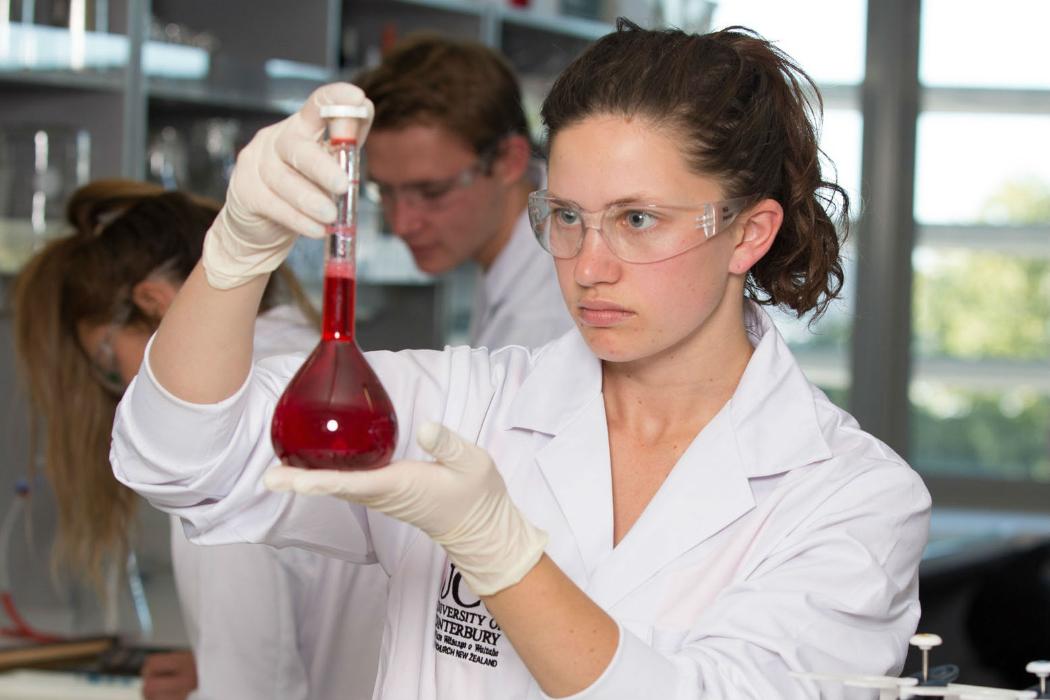 Chemistry student in lab with red liquid in flask Chemistry student in lab with red liquid